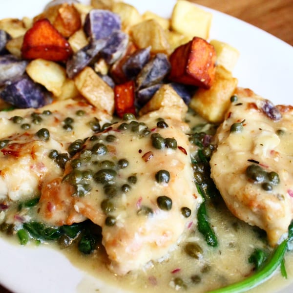 Chicken piccata with capers and a creamy sauce, served with roasted purple and orange potatoes.
