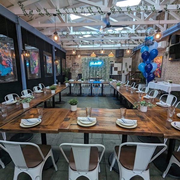 U-shaped table setup with white chairs, place settings, and potted plants in an Irish pub.