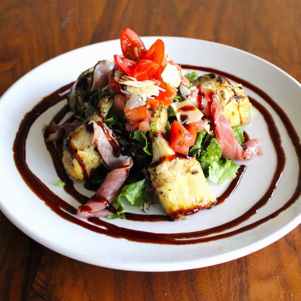A Harp And Fiddle salad with prosciutto, grilled artichokes, tomatoes, parmesan, and balsamic glaze.