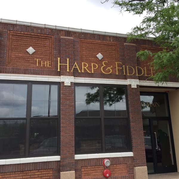The Harp And Fiddle restaurant exterior with brick facade, large windows, and gold lettering.